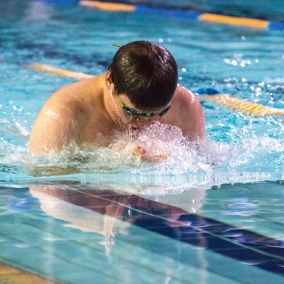 Up for a breath: A competitor busts it out in the pool in the breast-stroke event on Friday evening. 